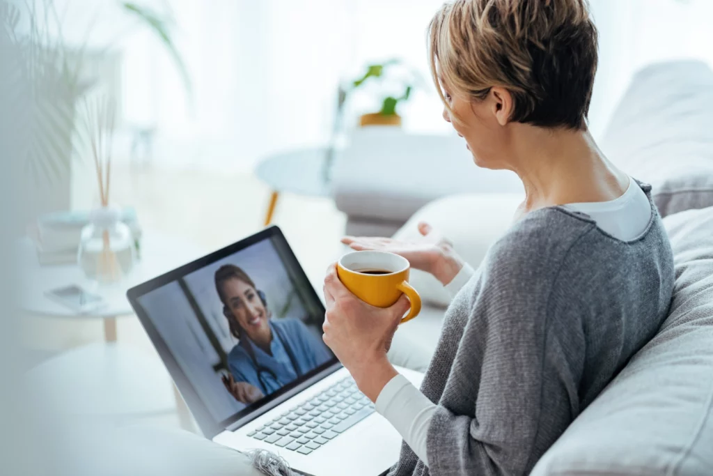 woman using laptop having video call with her doctor while sitting home
